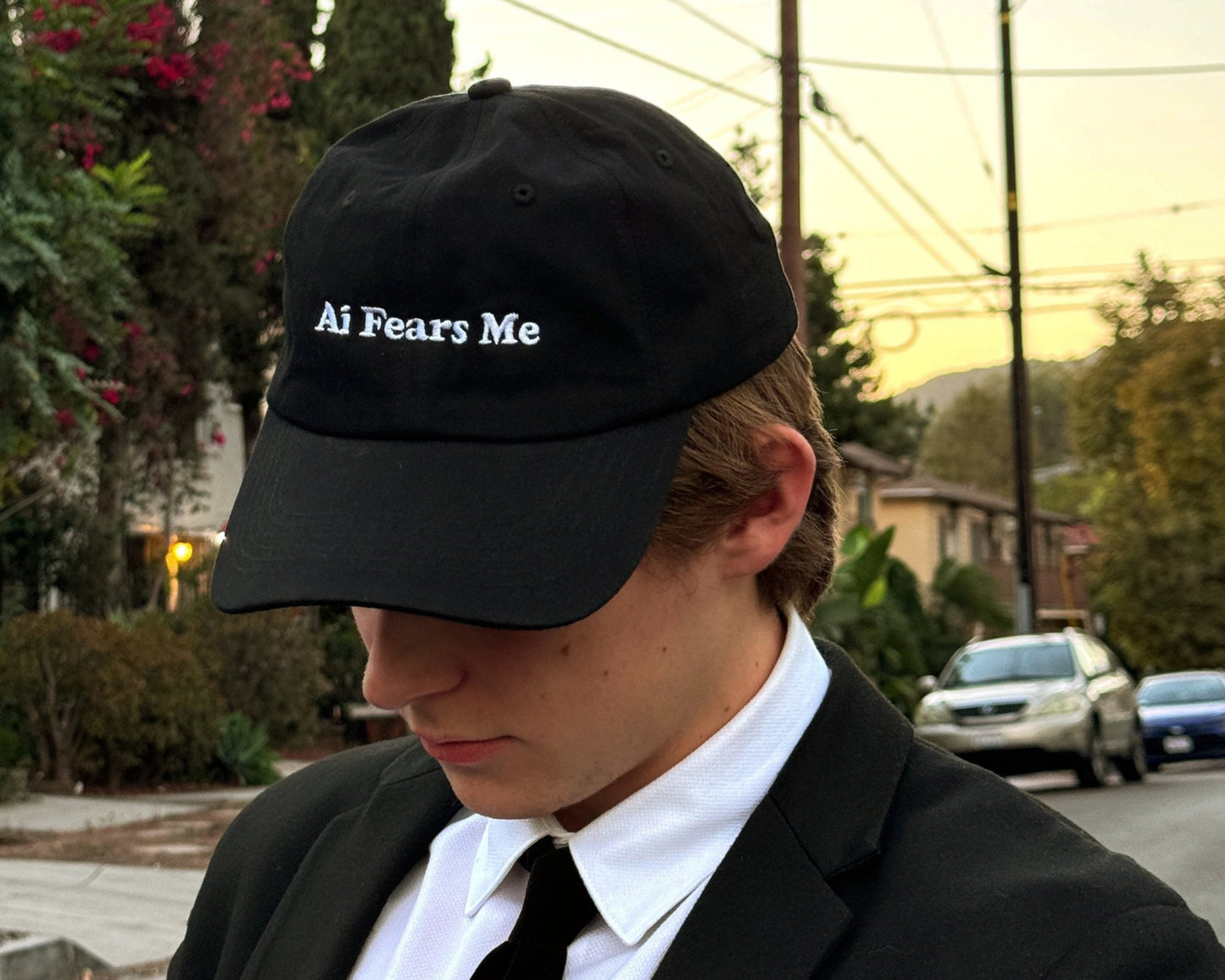 Person wearing a black dad hat with the words 'AI Fears Me' embroidered in white on the front, standing outdoors in a casual setting.